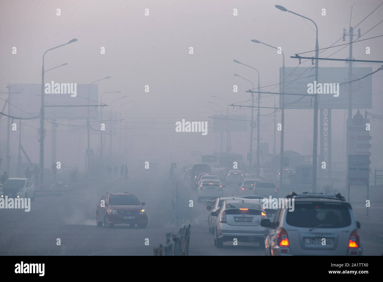Cars drive through thick pollution in Ulaanbaatar, Mongolia. Stock Photo