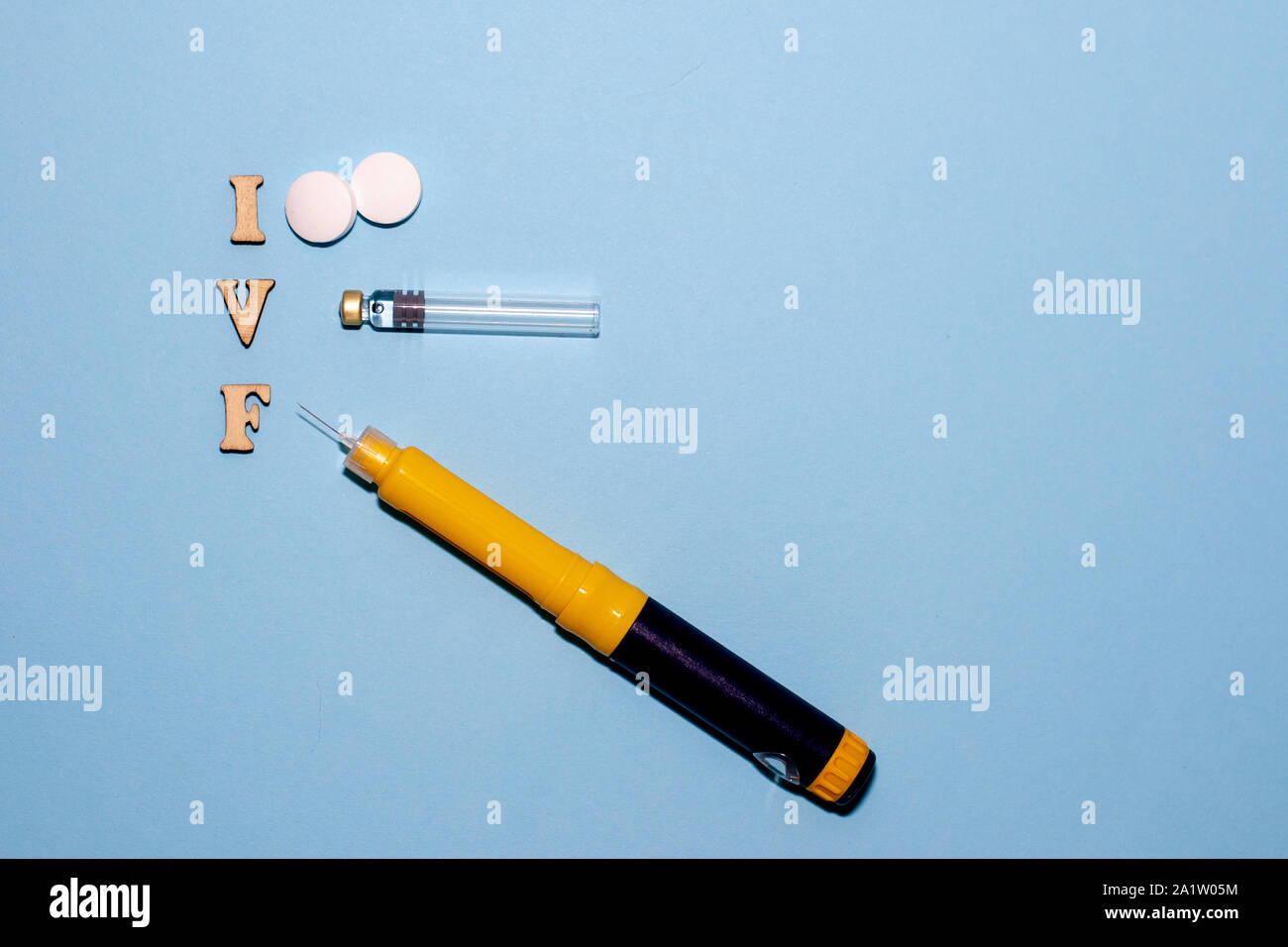 The abbreviation IVF is laid out in wooden letters on a blue background. In  vitro injection pen, tablet and ampoule. A syringe with a thin huge. IVF c  Stock Photo - Alamy