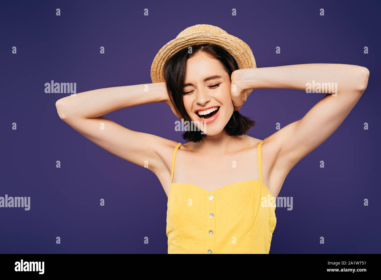 girl in straw hat with hands on ears screaming isolated on purple Stock Photo