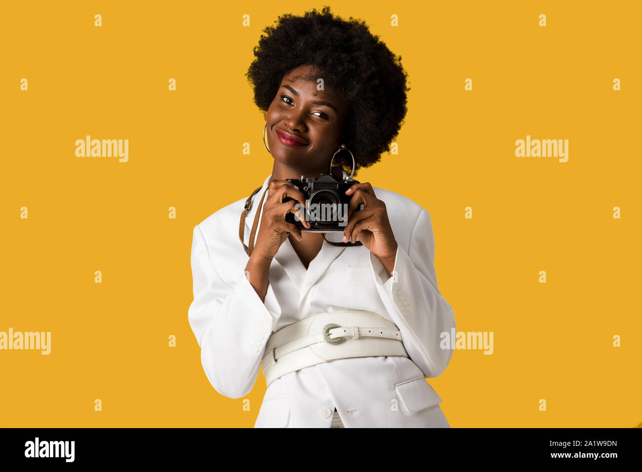 cheerful african american woman holding digitla camera isolated on orange Stock Photo
