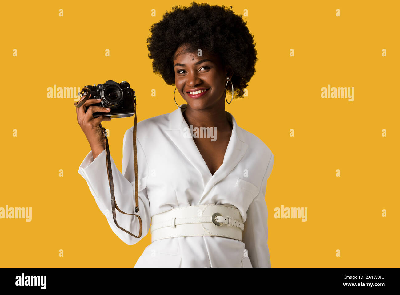 happy african american woman holding digitla camera isolated on orange Stock Photo