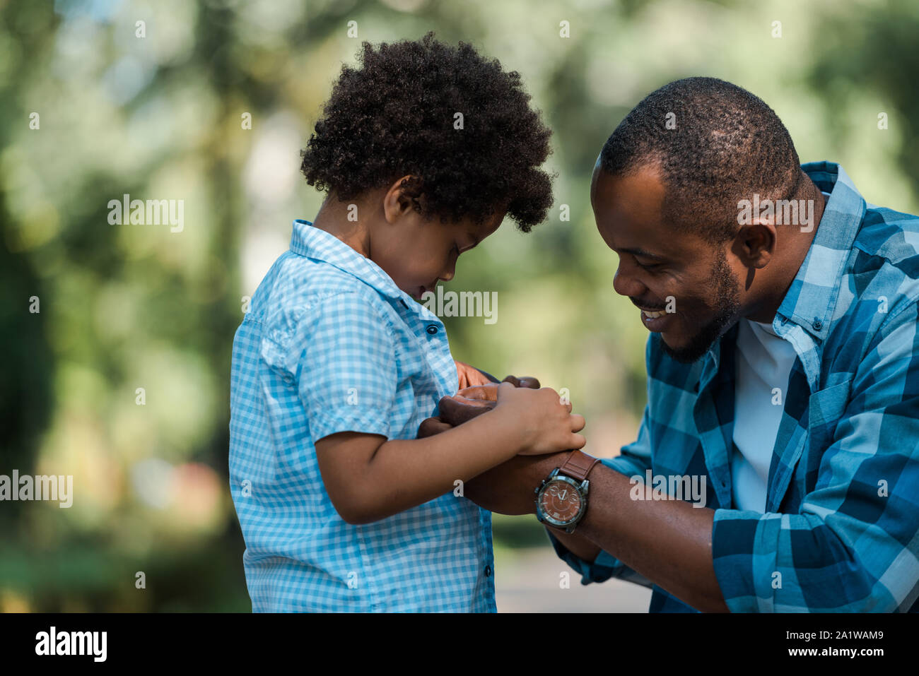 side view of cheerful african american father holding hands with sad ...