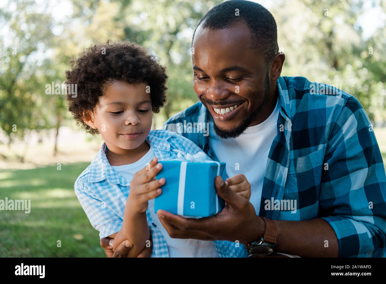 cheerful african american father and son looking at blue gift box Stock ...