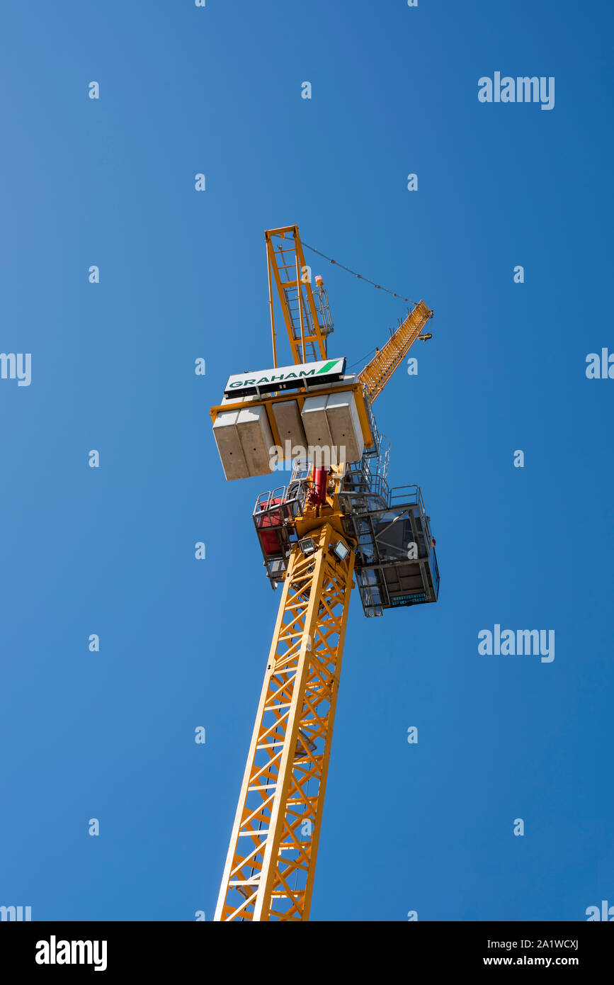 Yellow tower crane contrasting against blue sky background, showing ...