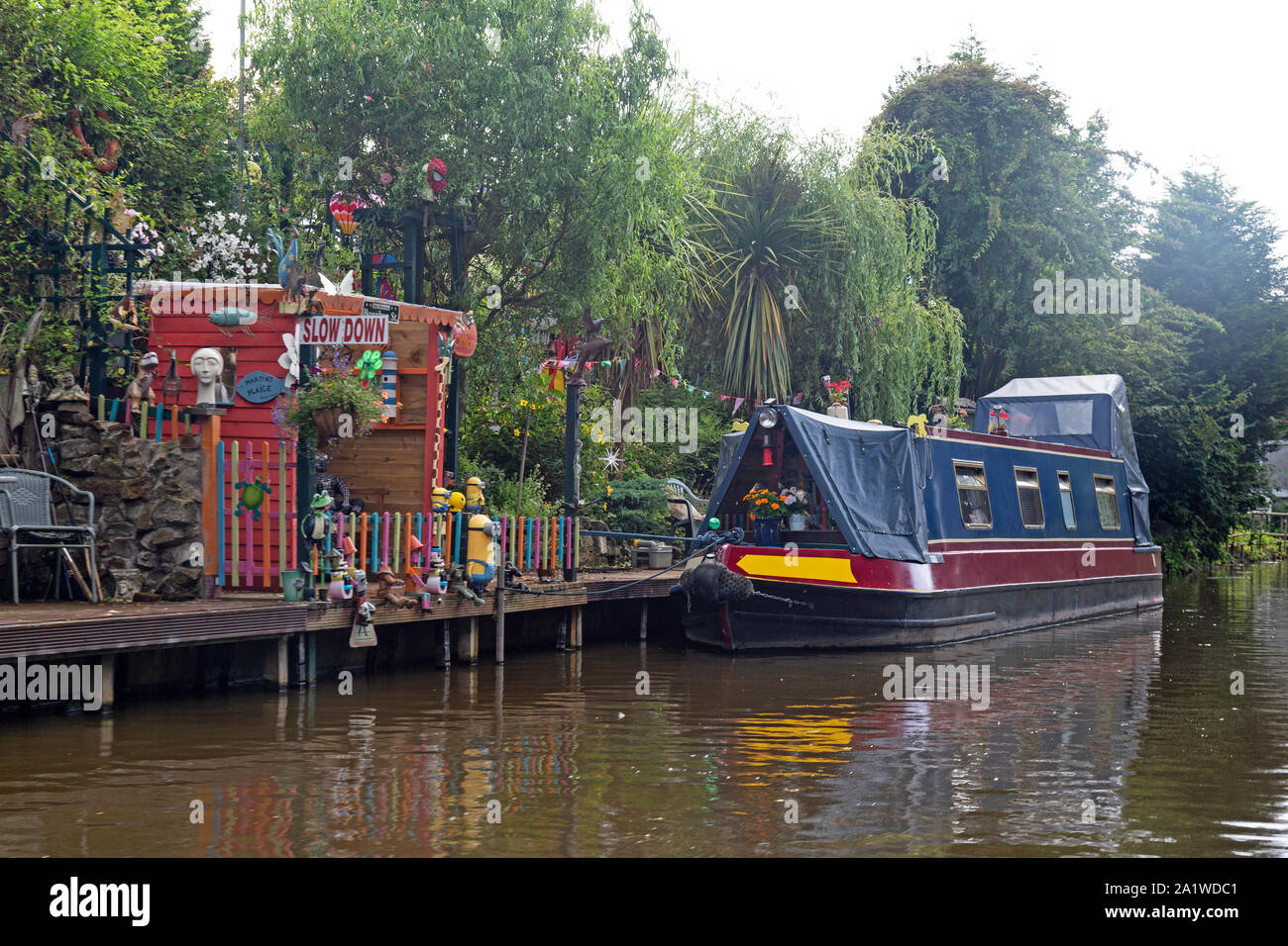 A Narrow Boat, or Barge, moored up alongside a colourful, fun, mooring on The Shropshire Union Canal in England. Stock Photo