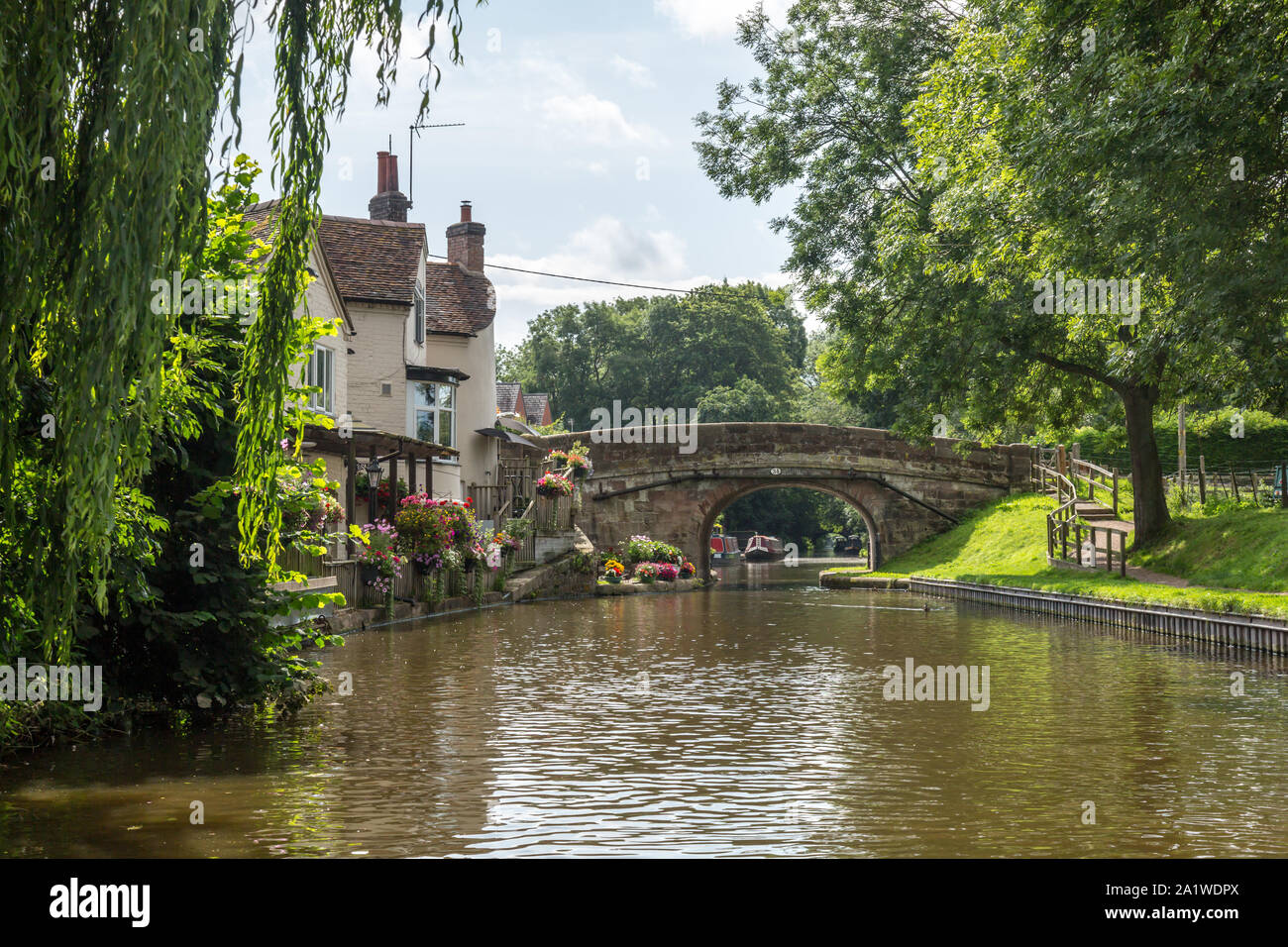 A brick built bridge over The Shropshire Union Canal in England, with the canal and buildings alongside. Stock Photo