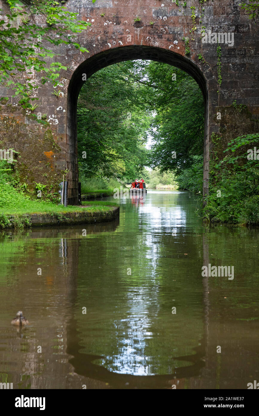A Narrow Boat, or Barge, approaching a brick bridge on The Shropshire Union Canal in England. Stock Photo