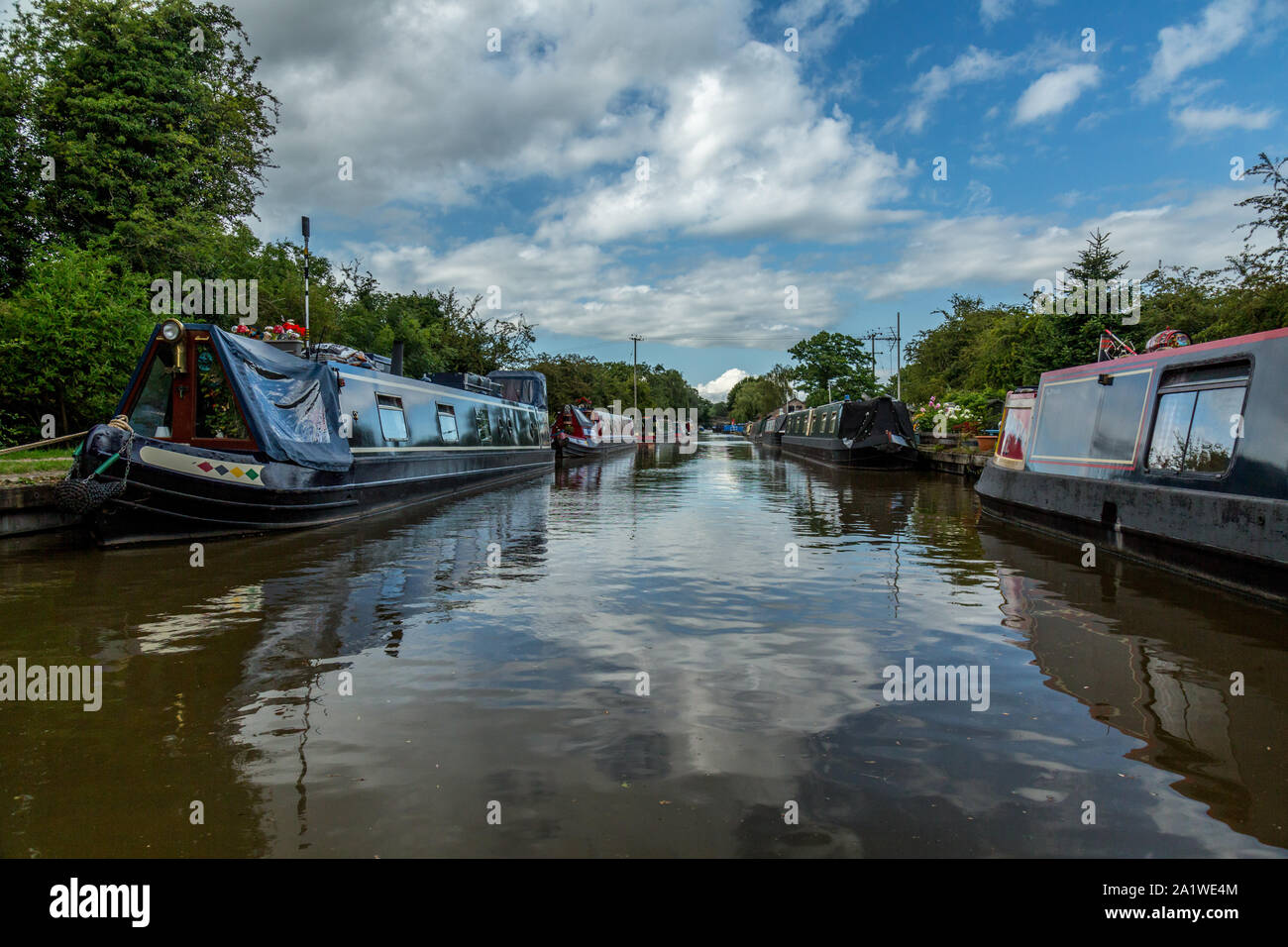 Narrow Boats, or Barges, moored up on either side on The Shropshire Union Canal in England. Stock Photo