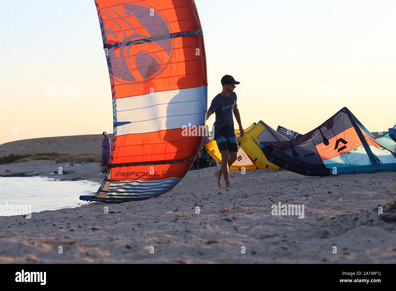 A kitesurfing coach helps safely land a colourful kite on an Egyptian beach island Stock Photo