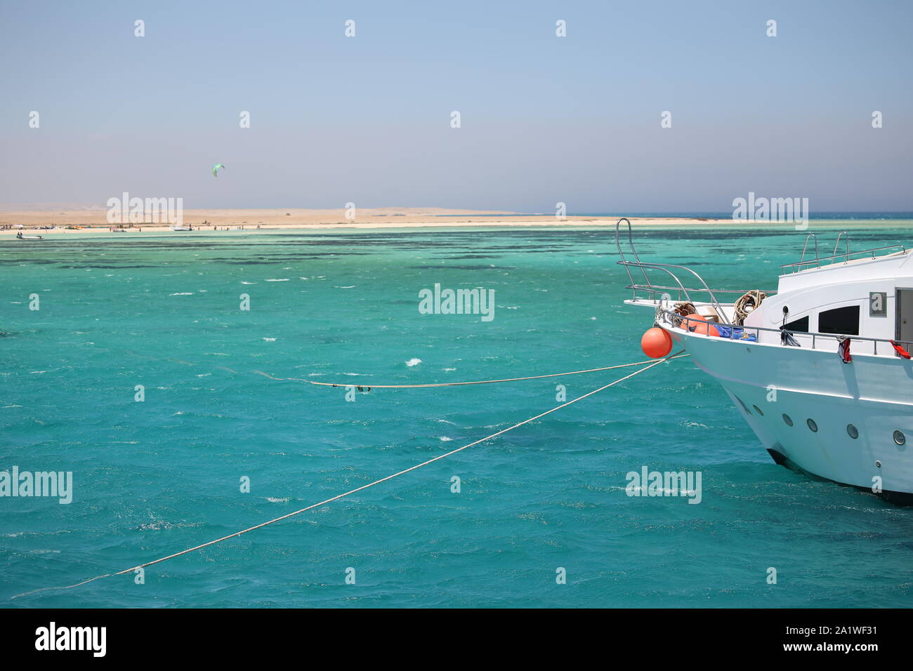 Motor yacht anchored of a deserted island in the Red Sea with kitesurfing in the background Stock Photo