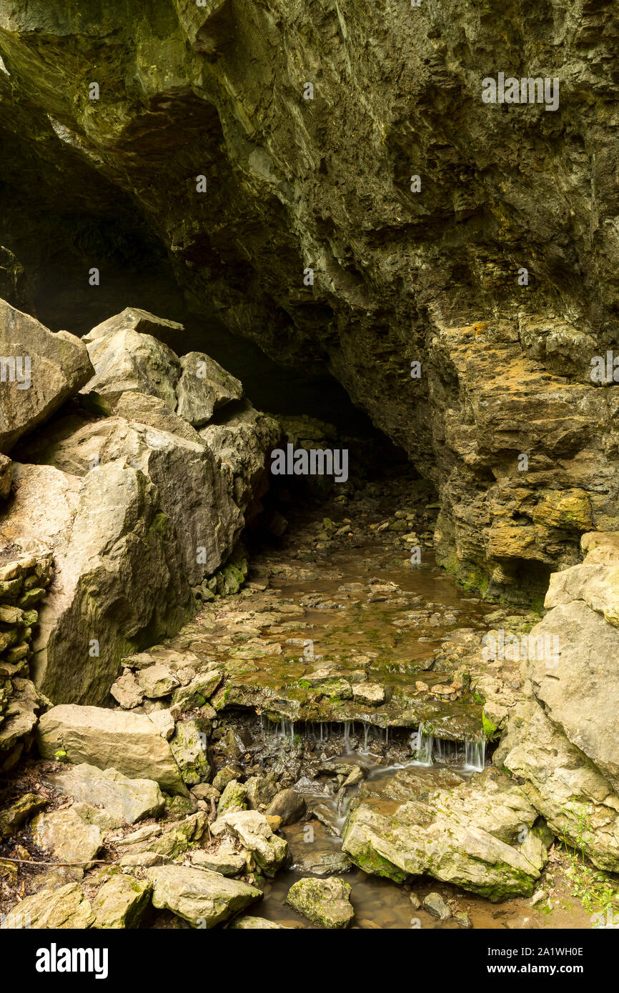 A Cave Entrance With A Stream Stock Photo