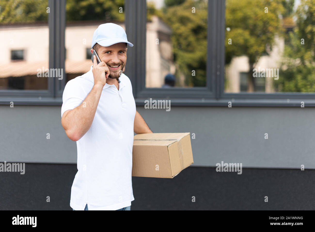 happy delivery man talking on smartphone while holding box Stock Photo
