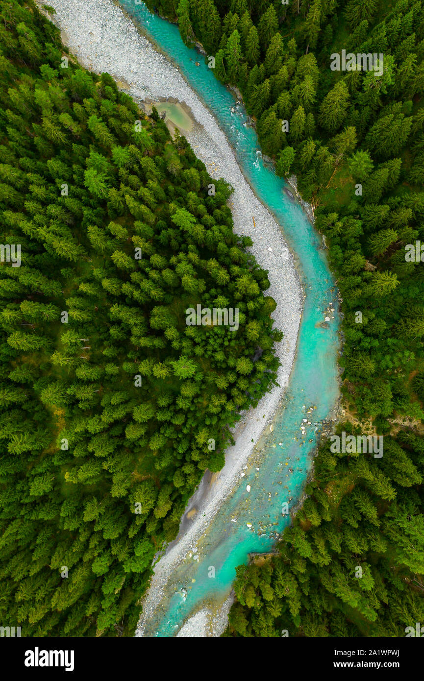 Inn River flowing in the forest in Switzerland. Aerial view from drone on a blue river in the mountains Stock Photo