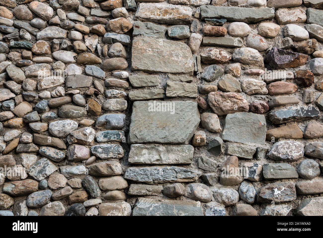Natural stone wall with colorful and different sized stones Stock Photo
