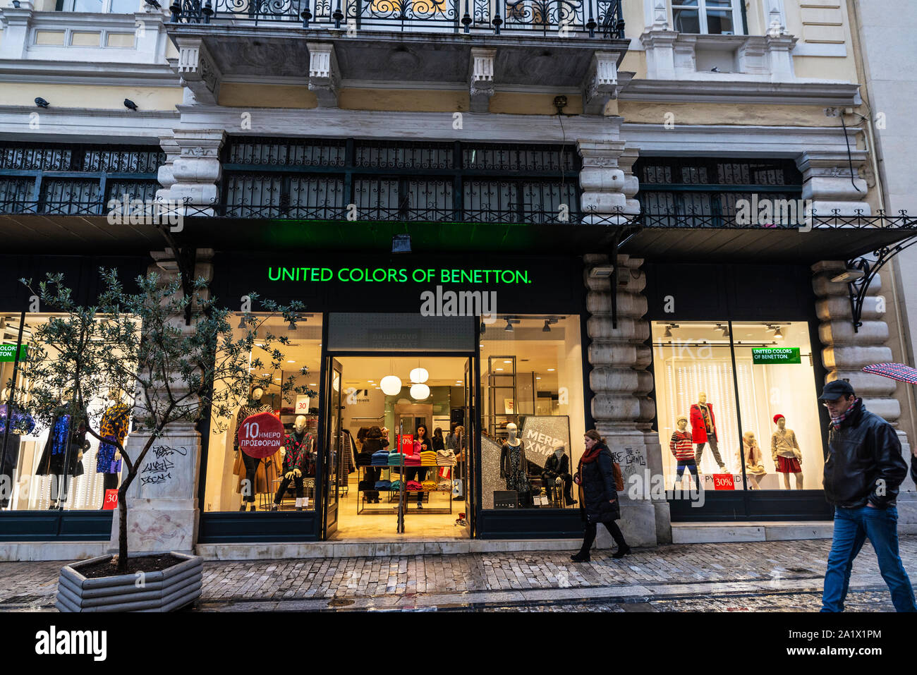Athens, Greece - January 4, 2019: Display of a United Colors of Benetton store at night with people around in Athens, Greece Stock Photo