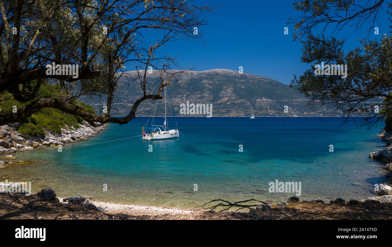Aerial photo of a sailing yacht at anchor in a sheltered Greek coastline in the clear blue Summer Mediterranean sea Stock Photo