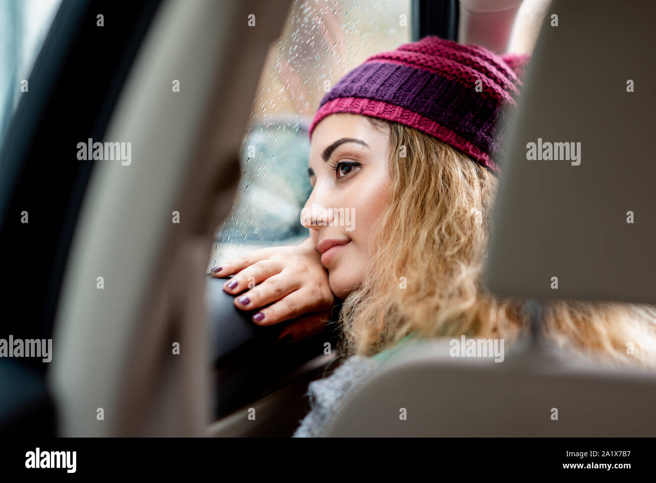 beautiful young woman looking to the rain from car window. Stock Photo