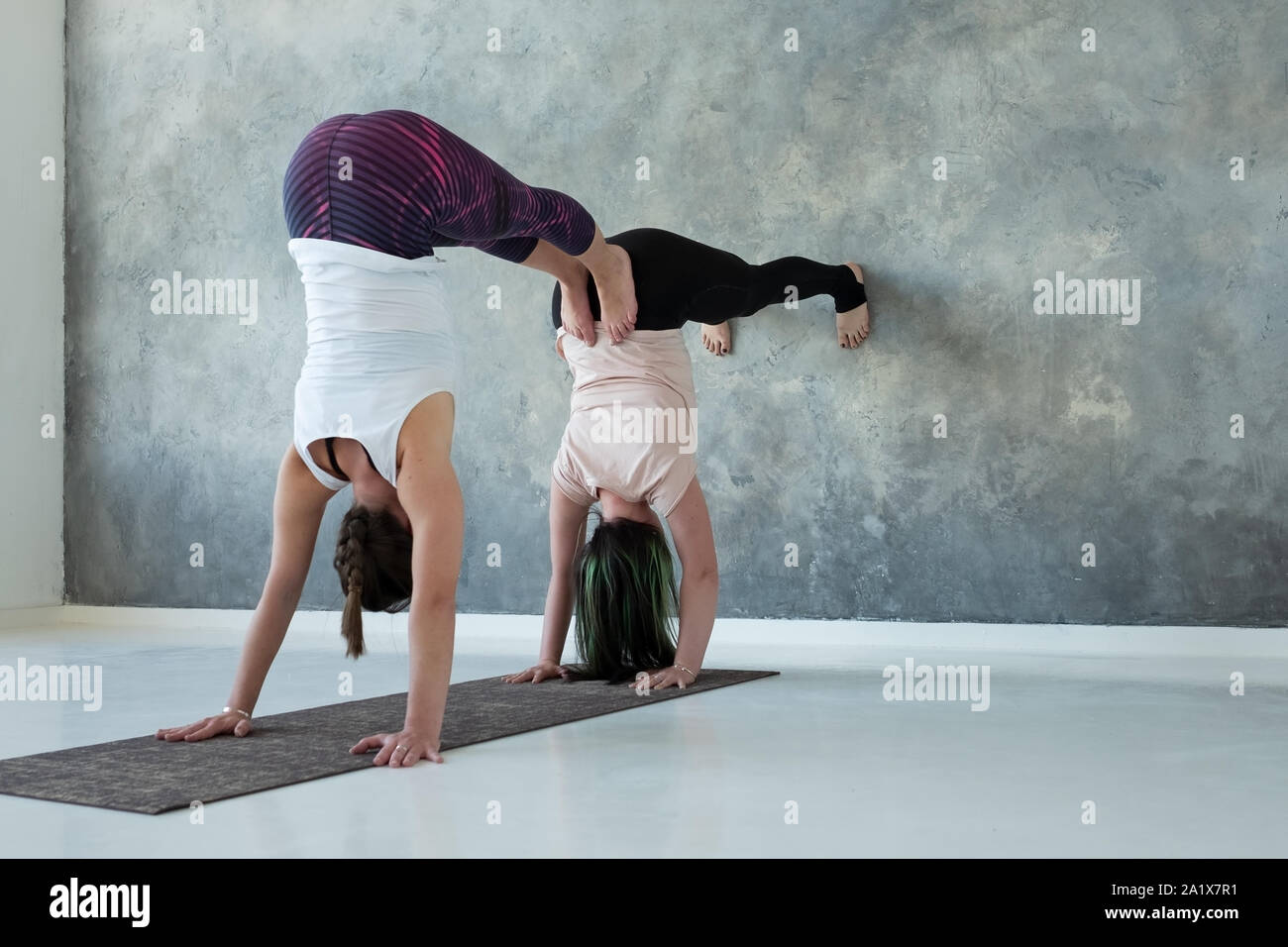 Women standing on hands near wall. Upside down yoga position Stock Photo