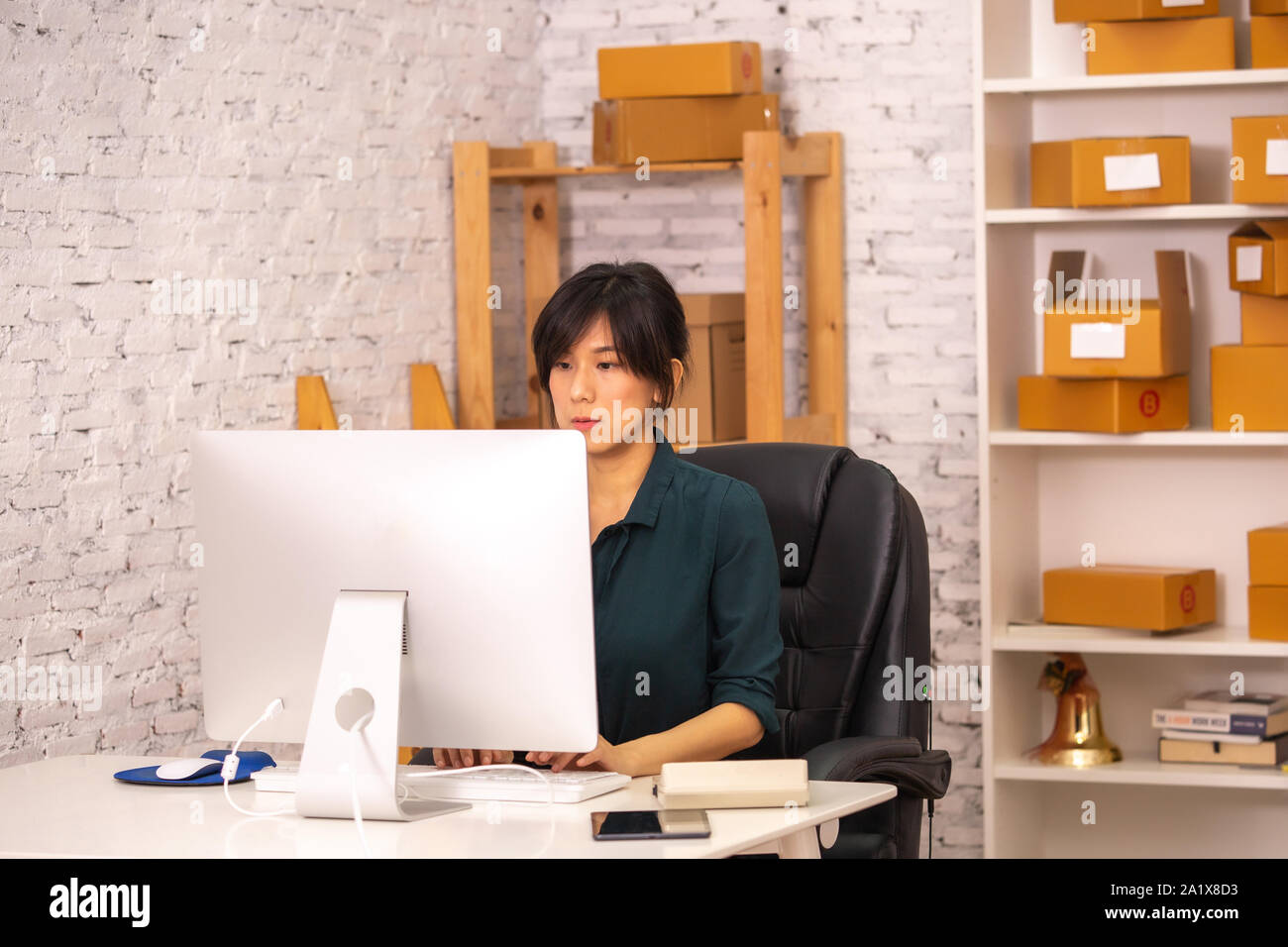 Determined Asian lady typing on computer keyboard while working with ...