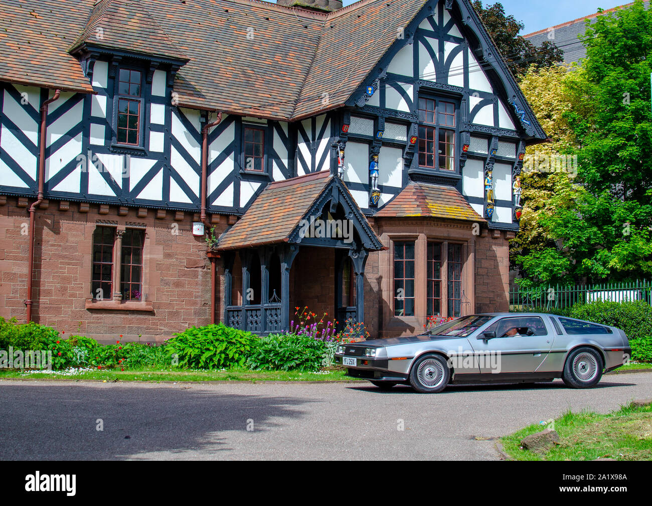 The classic DMC DeLorean car passing by a beautiful english Tudor style house called the Lodge. 'Brums and Buns' retro cars festival at Chester. Stock Photo