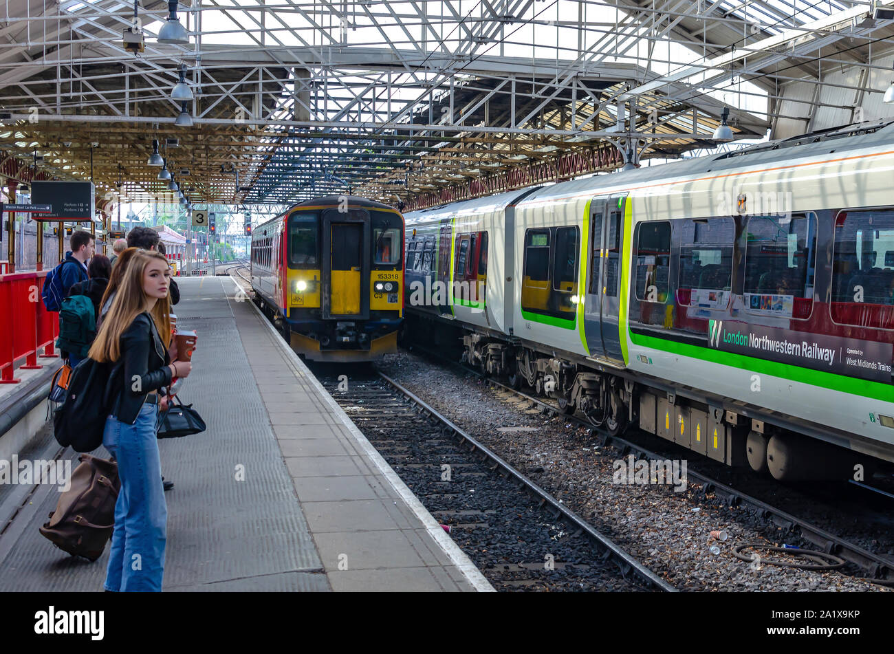 The train arriving at Crewe (Cheshire, England) railway station and commuters waiting for it on the platform number 3. Stock Photo