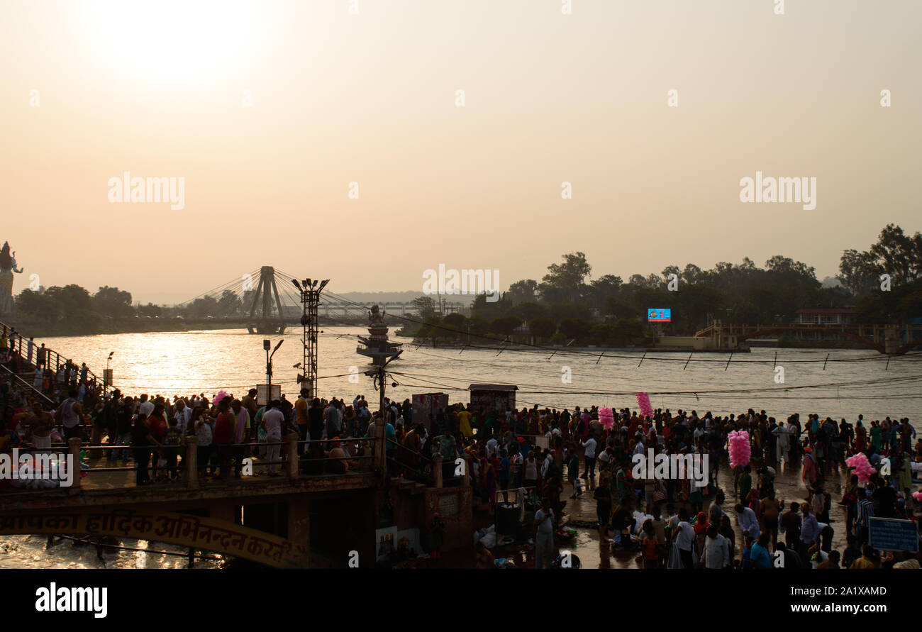 Heavy crowd going to take bath into ganga river due to saavan festival at haridwar bridge temple sky. Stock Photo