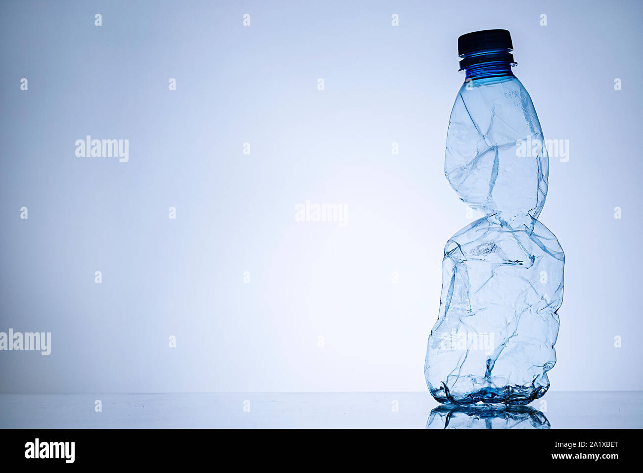 Side border with copy space of a crumpled empty clear plastic bottle standing upright in a concept of disposable household waste and pollution Stock Photo