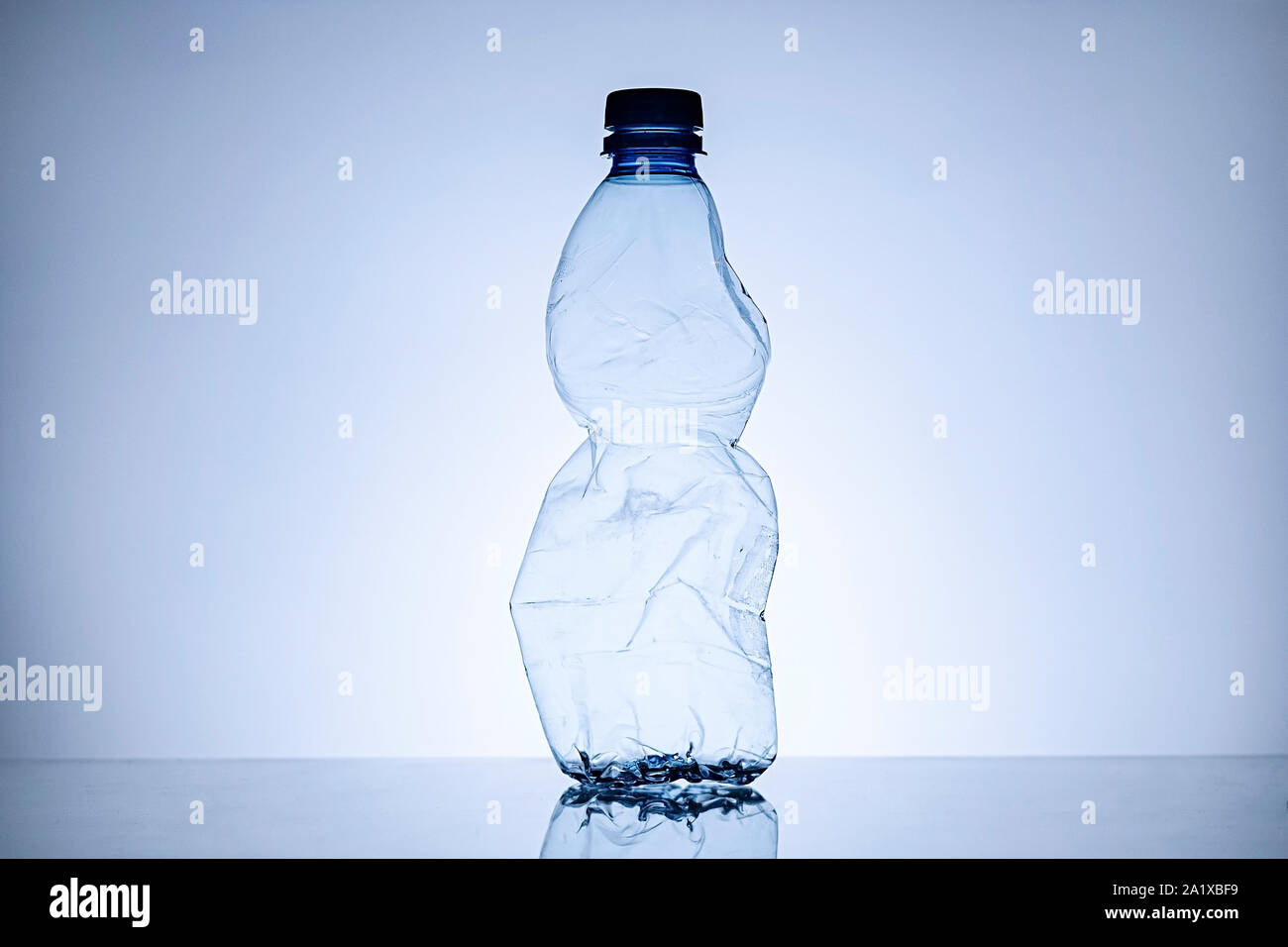 Side border with copy space of a crumpled empty clear plastic bottle standing upright in a concept of disposable household waste and pollution Stock Photo