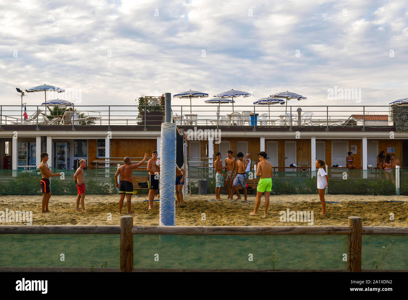 A coach teaches beach volleyball to a group of boys on the sandy beach of a bathing establishment in summer, Lido di Camaiore, Tuscany, Versilia,Italy Stock Photo