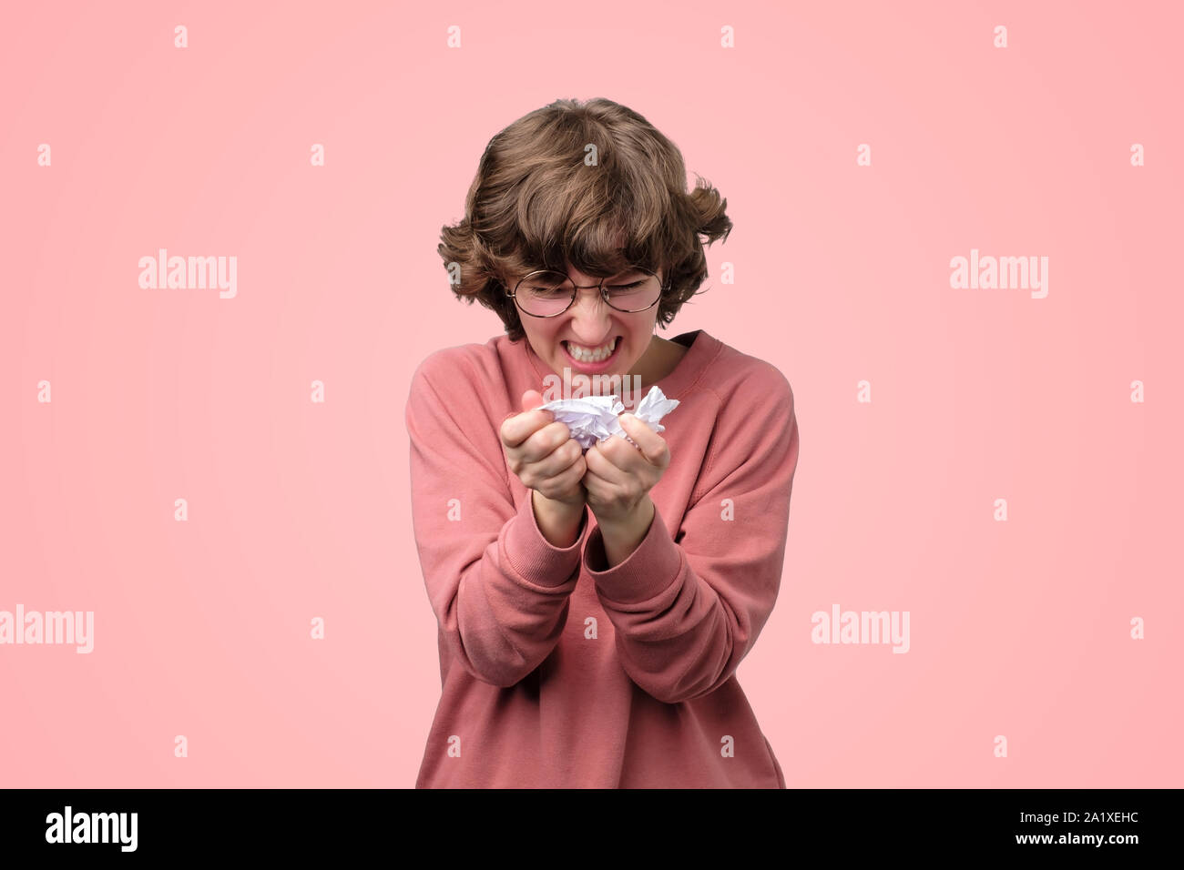 Angry young woman furiously tearing paper in pieces. Be angry of mistake or failure in exam. Studio shot Stock Photo