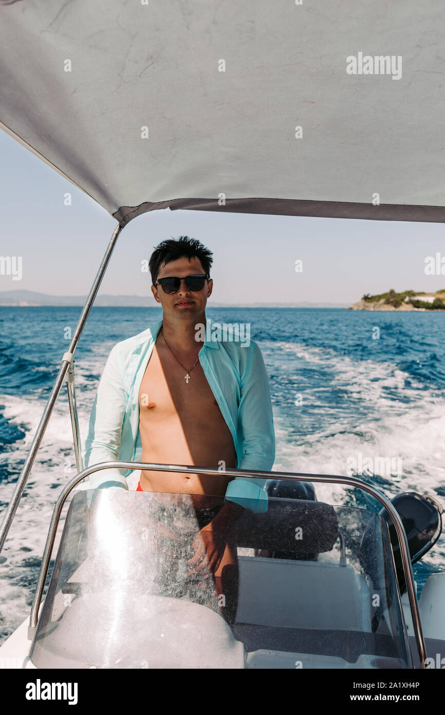 Man in sunglasses driving and navigating yacht in the sea. Sailing man on  yacht in ocean Stock Photo - Alamy