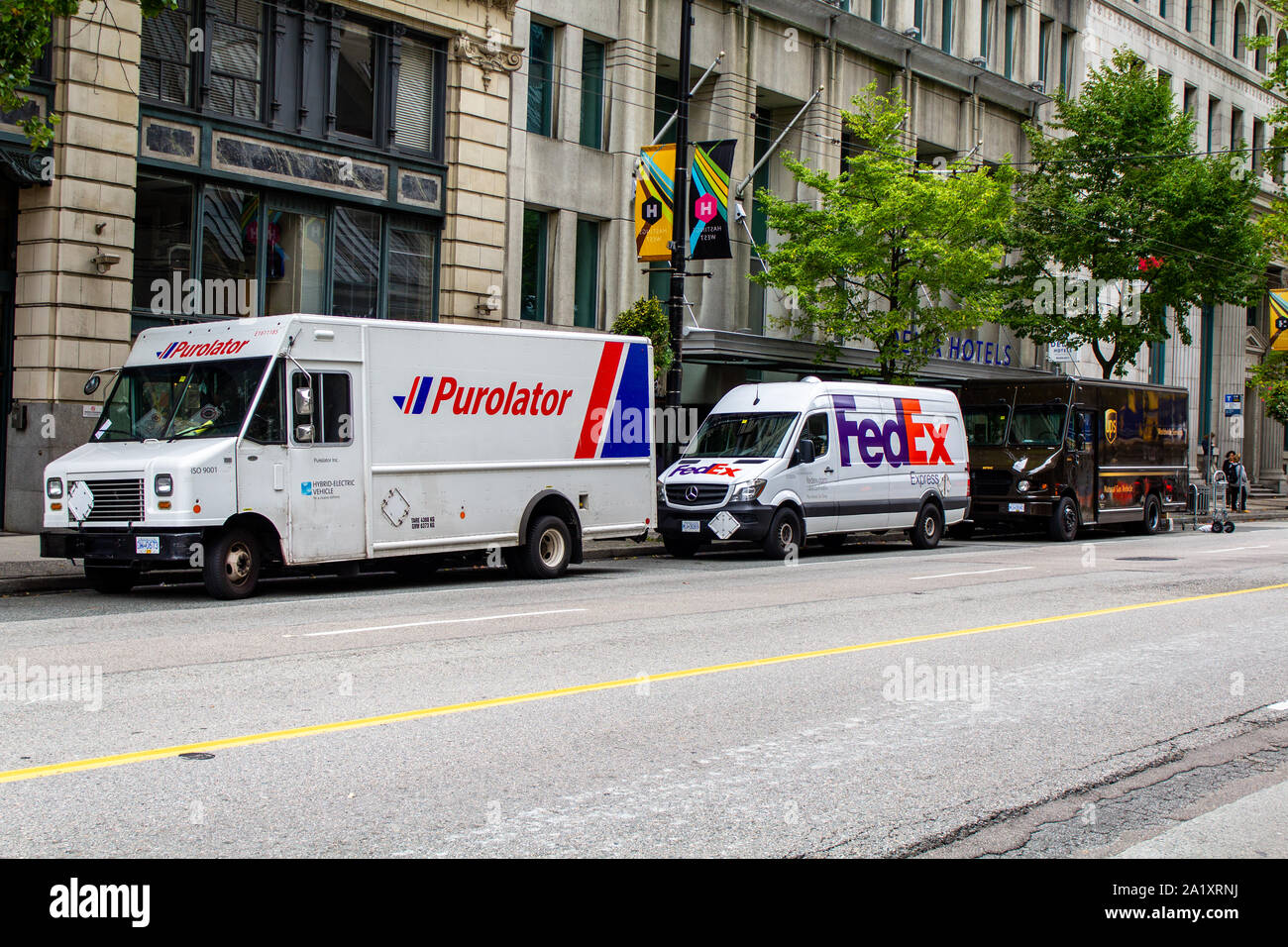 Purolator, FedEx and UPS trucks parked on the street Stock Photo