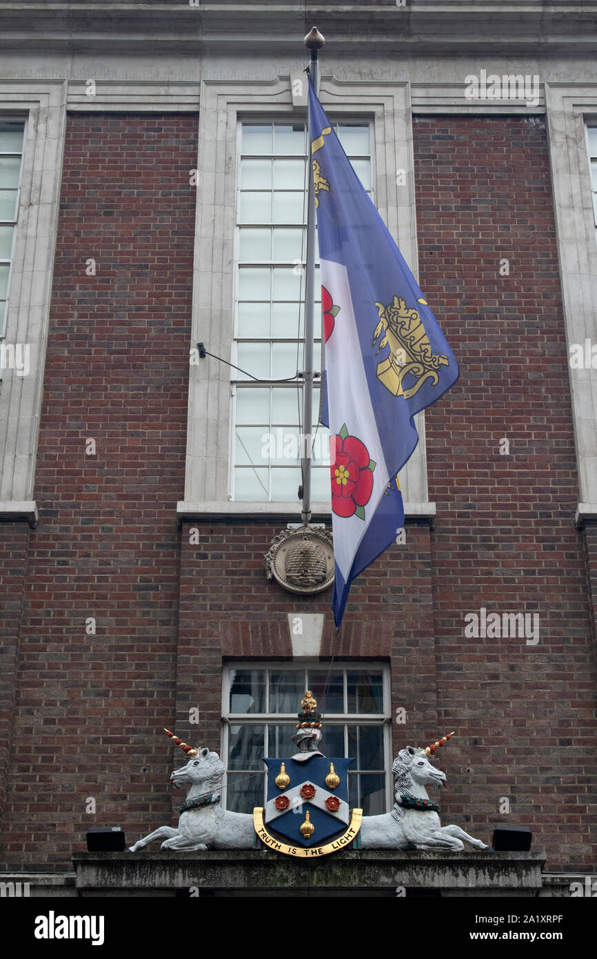 The coat of arms and flag above the entrance to The Worshipful Company of Apothecaries outside the London livery hall, Black Friars Lane, London UK Stock Photo