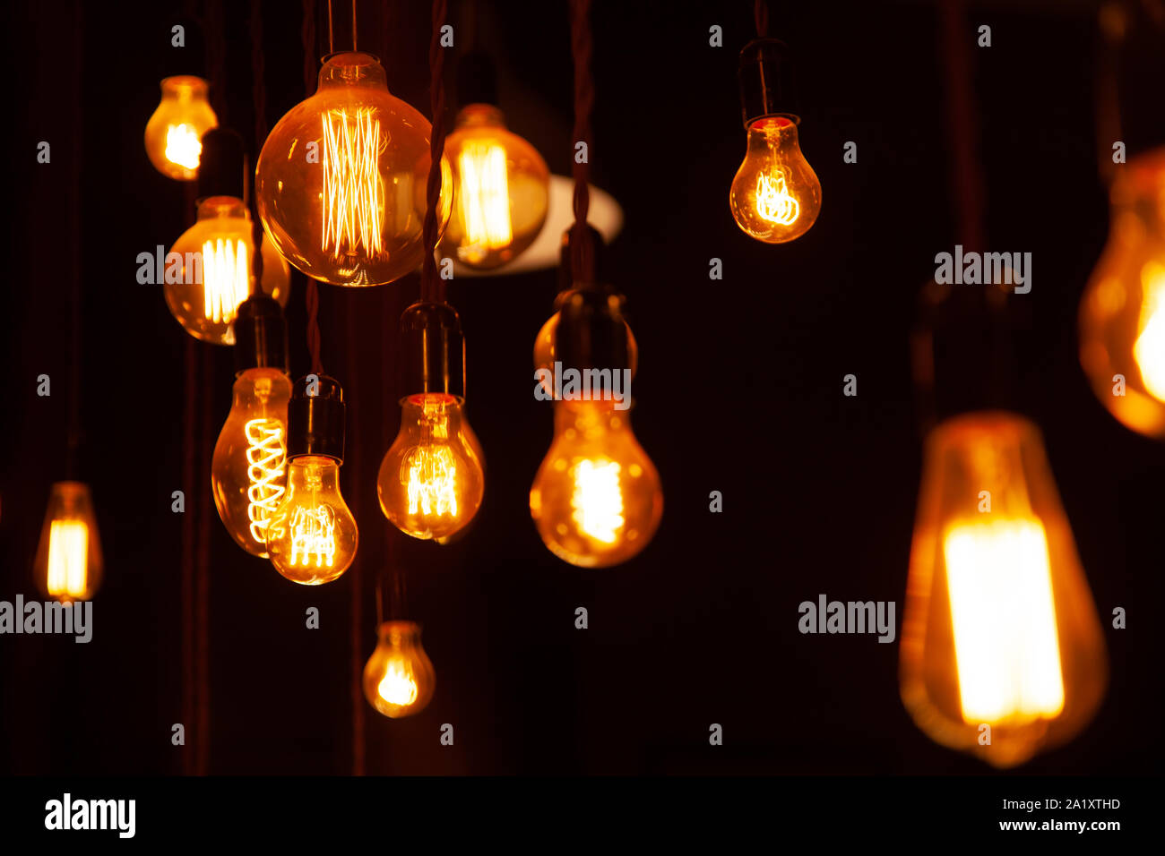 classic different retro light bulbs hanging on brick wall background at night. Stock Photo