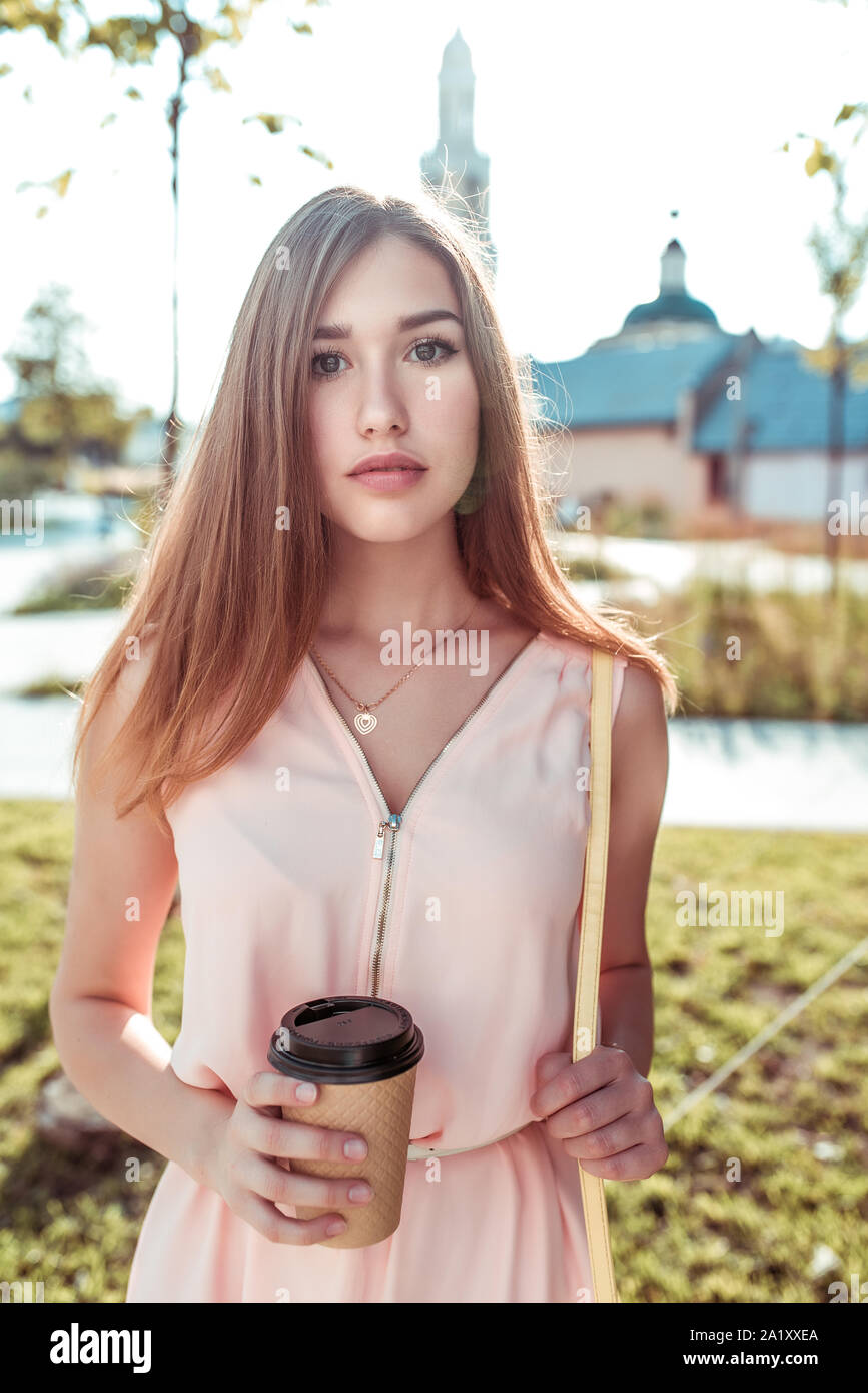 Girl student summer city stands autumn spring, pink dress, a hand in