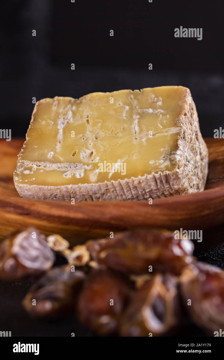 piece of old blue cheese and a branch of dates  lie on a wooden dish Stock Photo