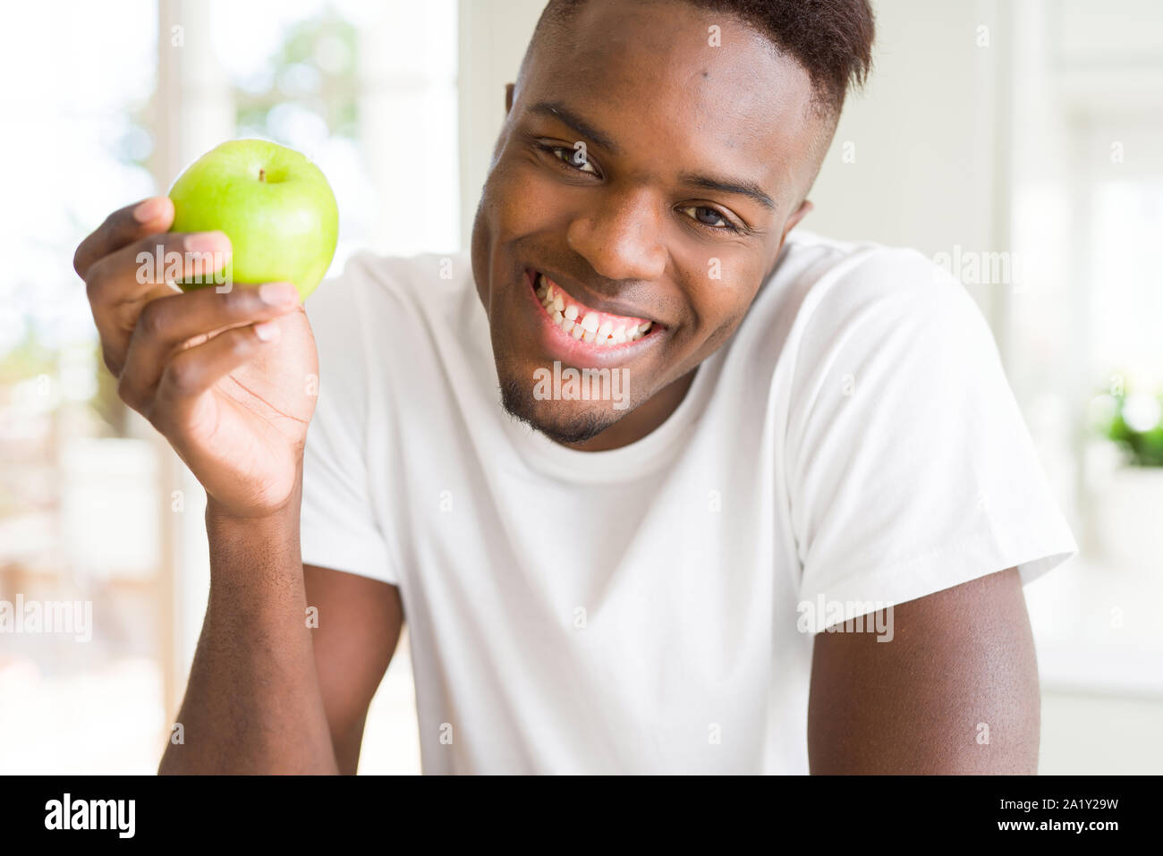 Young african american man eating a healthy green apple Stock Photo - Alamy