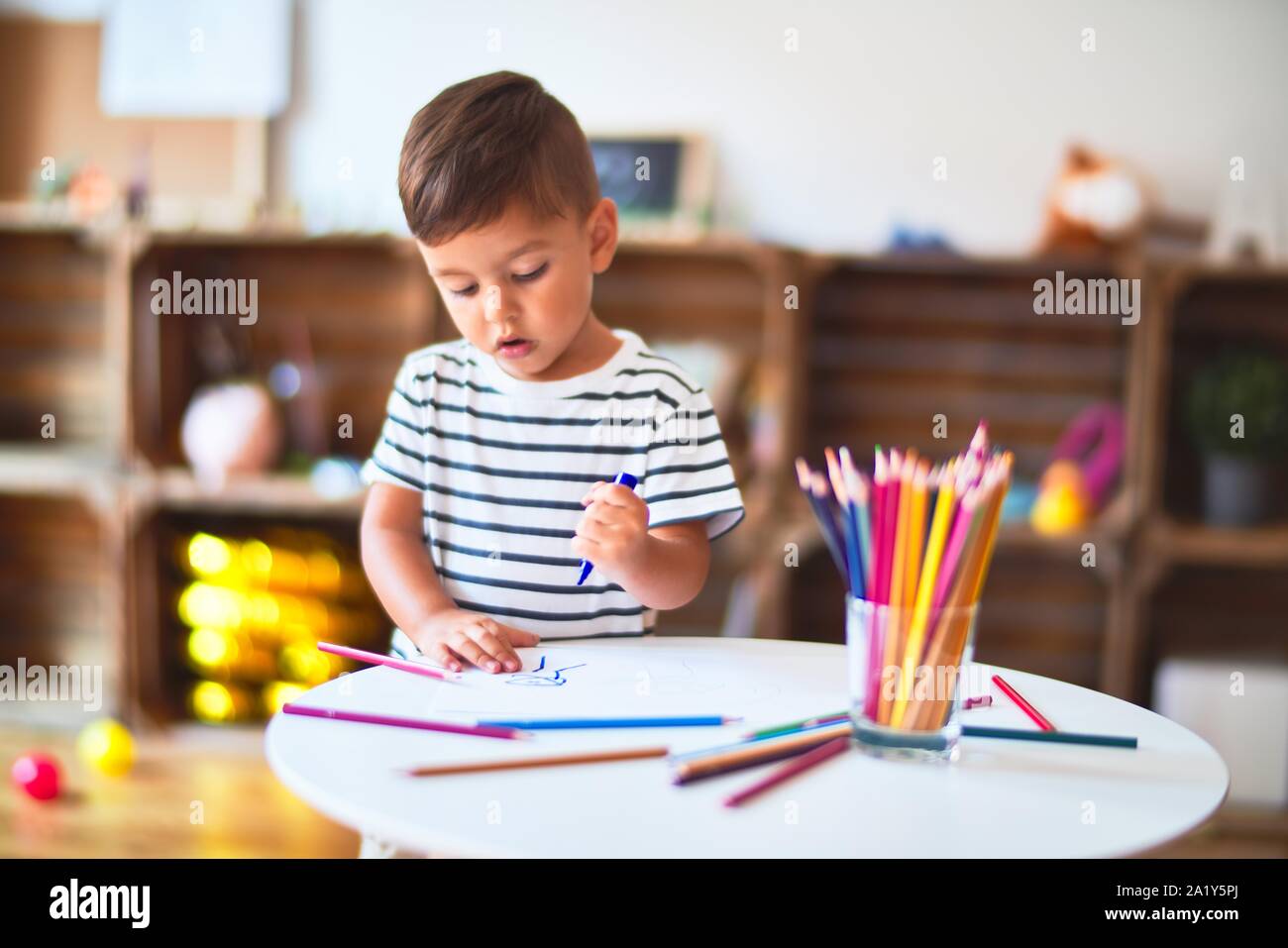 Beautiful toddler boy drawing cute draw using colored pencils at ...