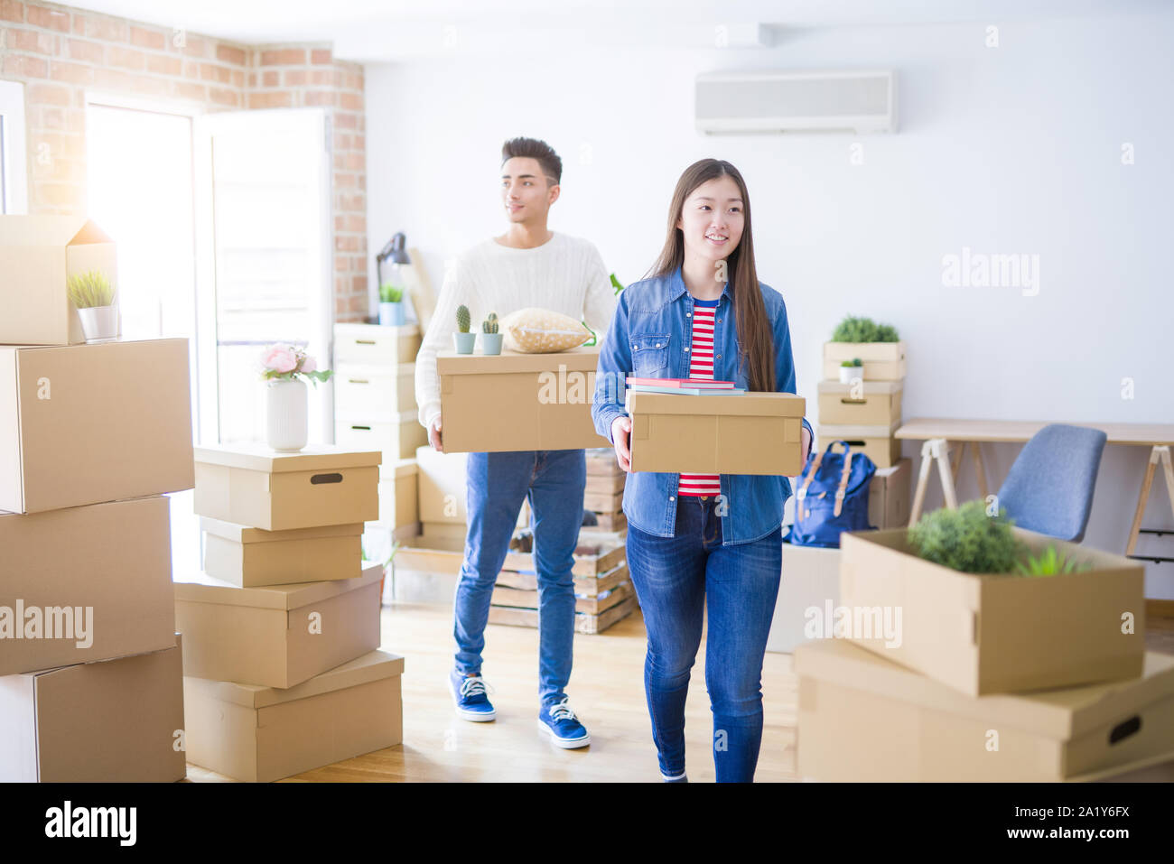 Beautiful young asian couple looking happy holding cardboard boxes ...
