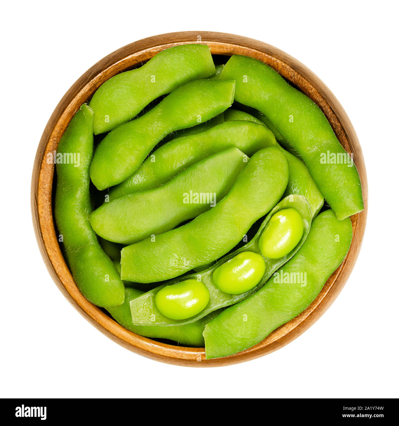 Green soybeans in the pod, edamame, in wooden bowl. Unripe soya beans, also Maodou. Glycine max, a legume, edible after cooking. Protein source. Stock Photo