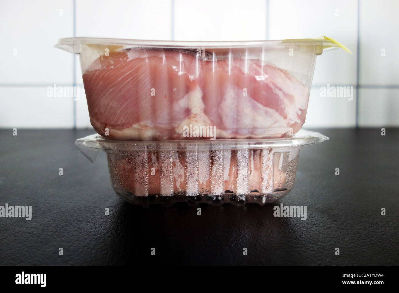 raw chicken meet packed into single-use plastic boxes on counter top in the kitchen. The amount of plastic waste produced by a single household is sho Stock Photo