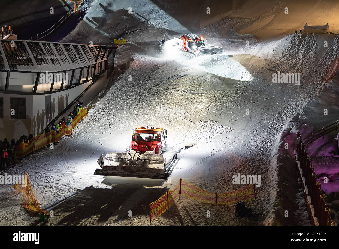 Two snowcat ratrack machines making night show performance on snow pister hill at alpine skiing resort Ischgl in Austria Stock Photo
