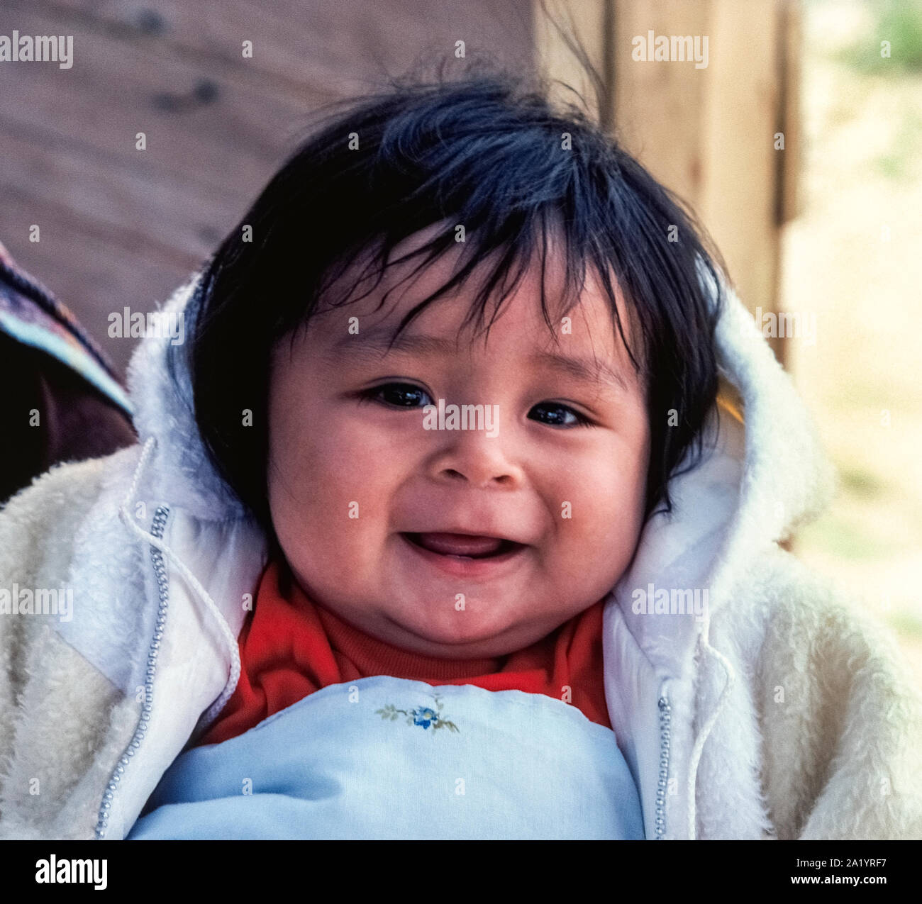 A smiling baby girl has the black hair and dark brown eyes that help  identify her as a Navajo Indian, one of the Native American peoples that  live in the Southwestern United