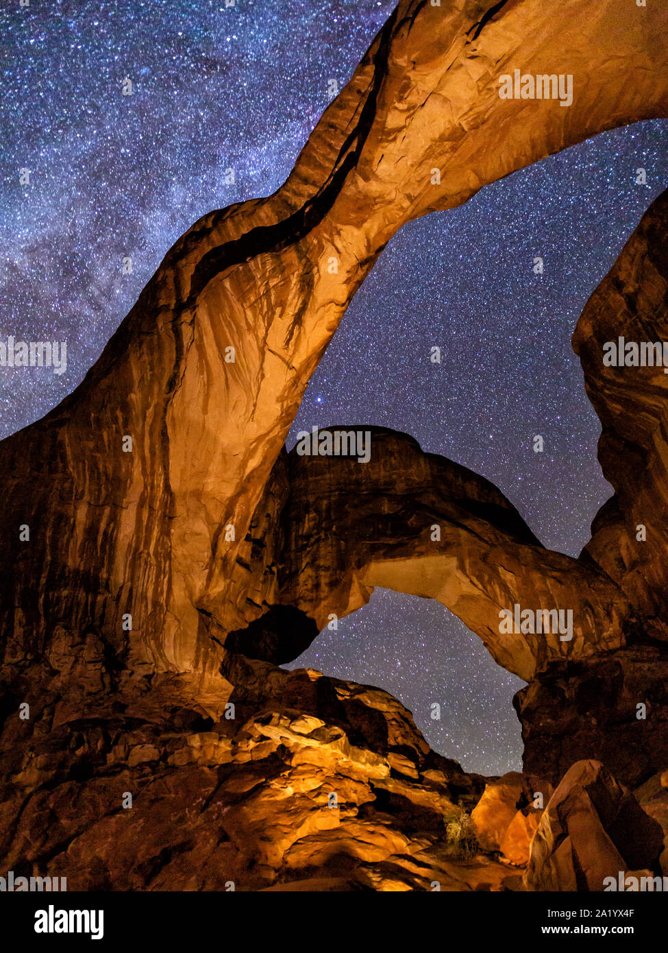 The inimitable Double Arch lit from within against the backdrop of the Milky Way in Arches National Park, Utah. Stock Photo