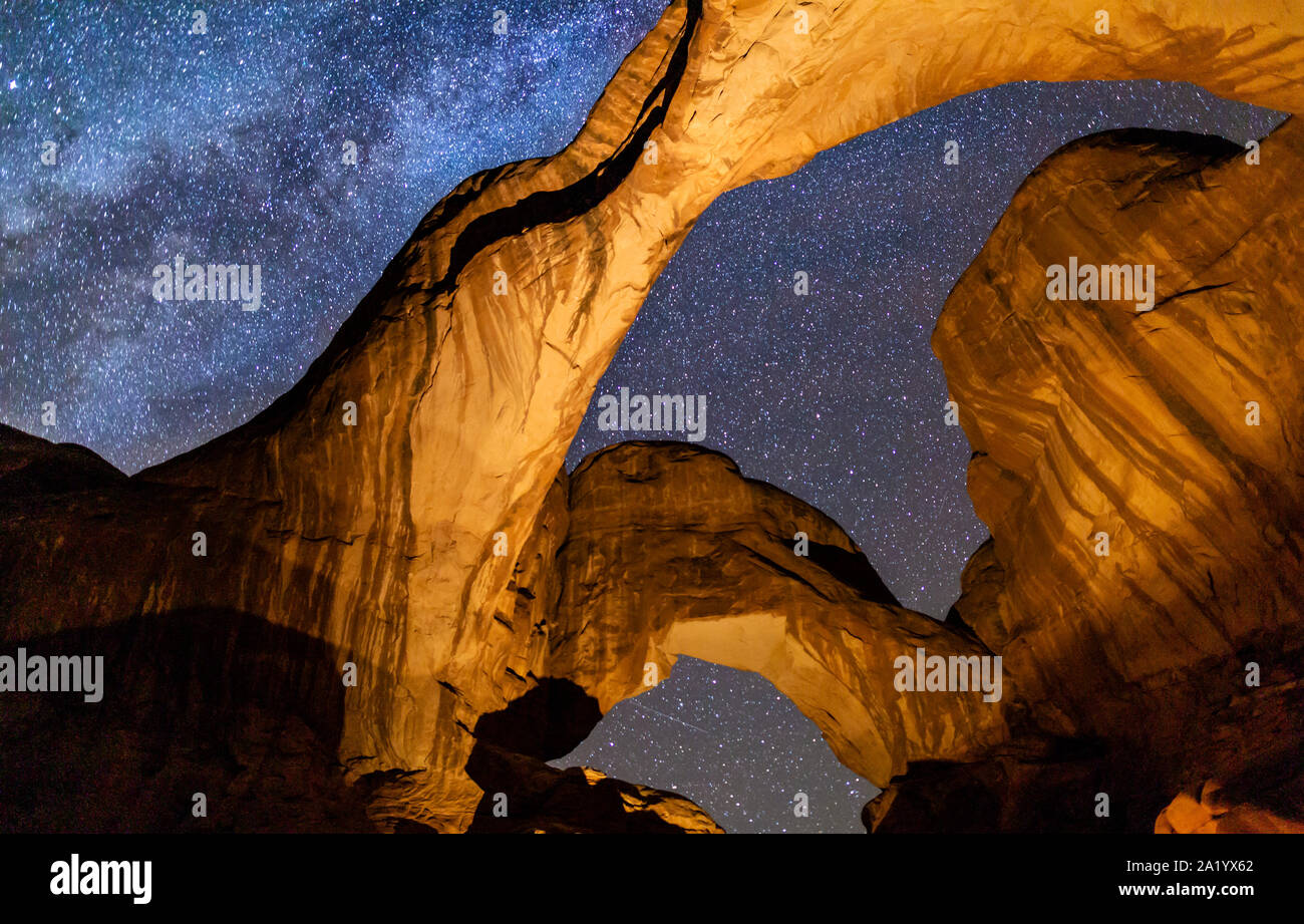 Looking up at Iconic Double Arch illuminated against a star-filled Milky Way in Arches National Park in Moab, Utah. Stock Photo