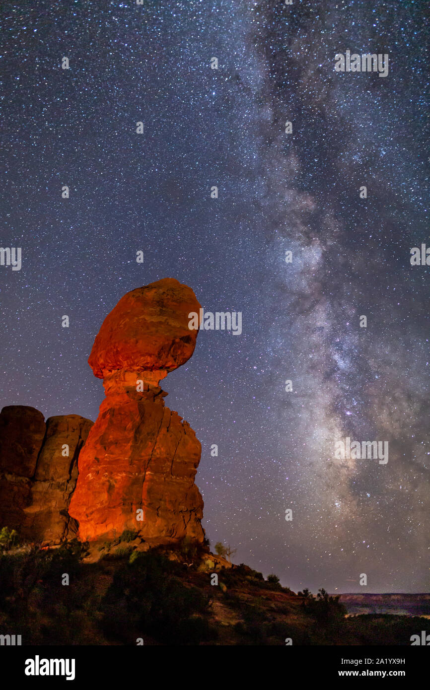 Iconic Balanced Rock illuminated against a star-filled Milky Way in Arches National Park in Moab, Utah. Stock Photo