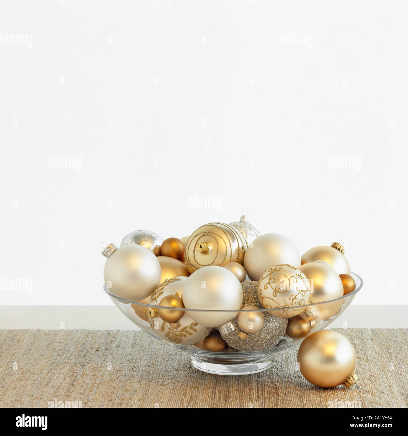 Beautiful, fancy silver and gold Christmas ornaments baubles in glass bowl with white background. Simple, modern, luxury holiday home interior decor. Stock Photo