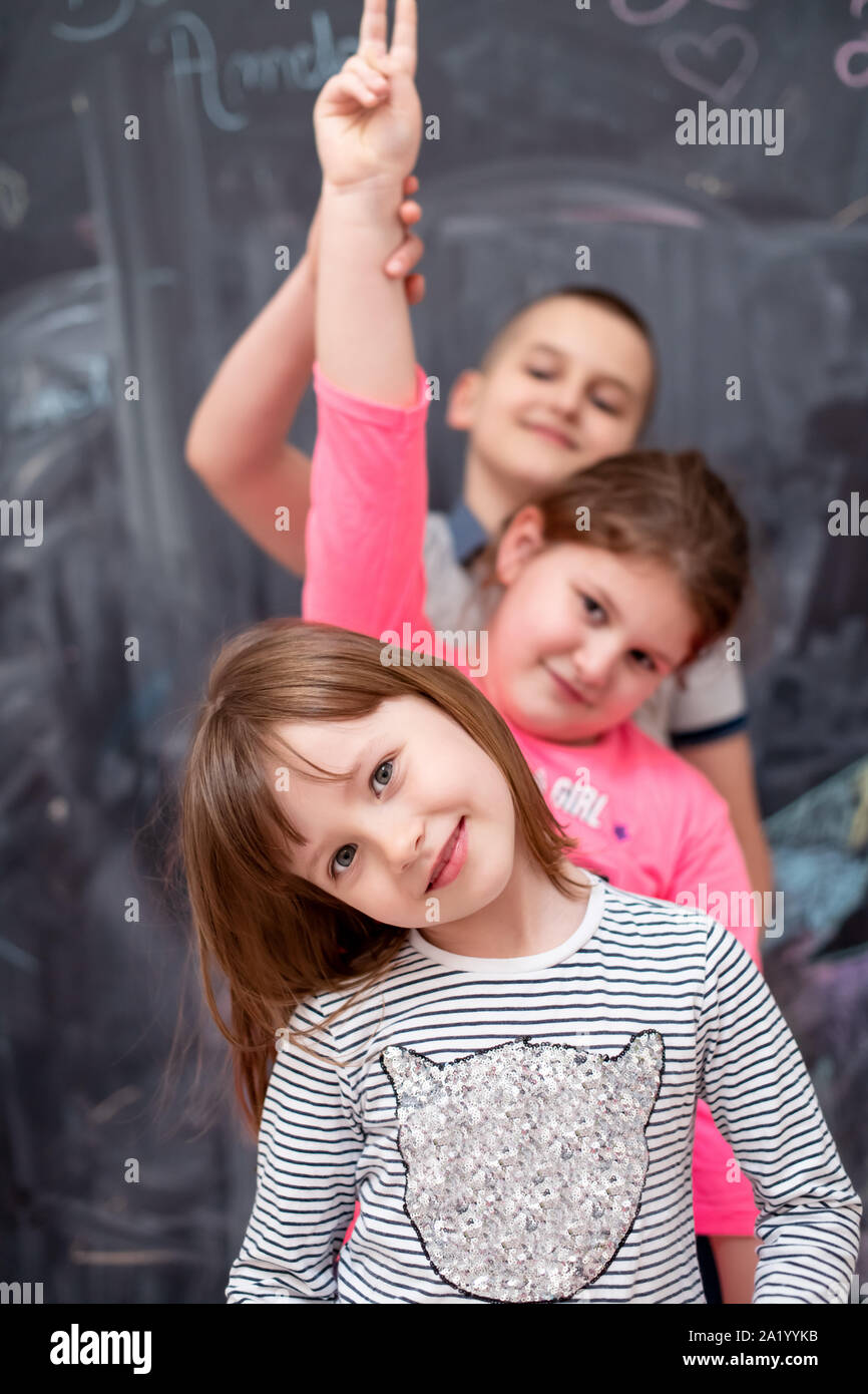 group portrait of happy childrens standing one behind the other while having fun in front of black chalkboard Stock Photo