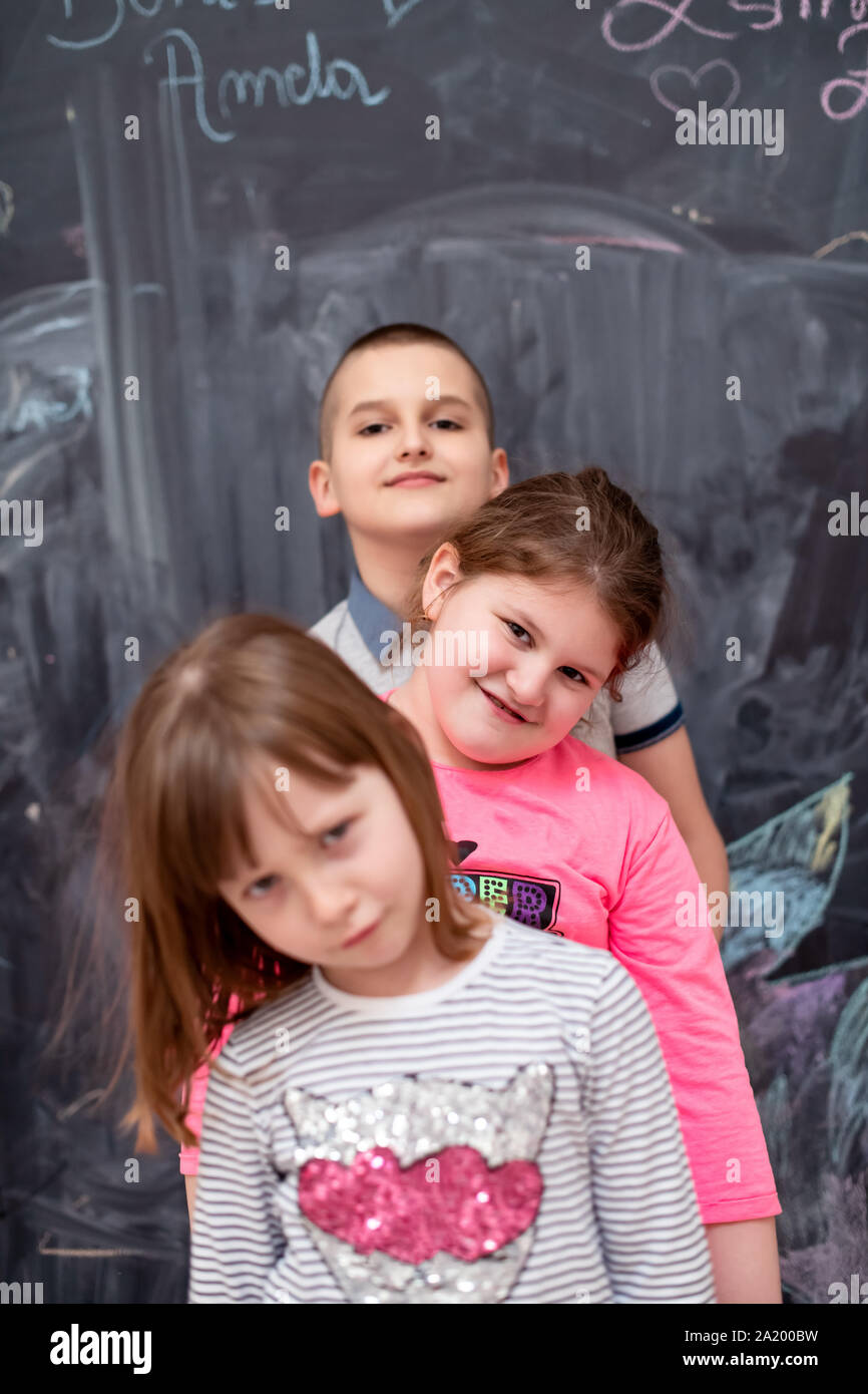 group portrait of happy childrens standing one behind the other while having fun in front of black chalkboard Stock Photo