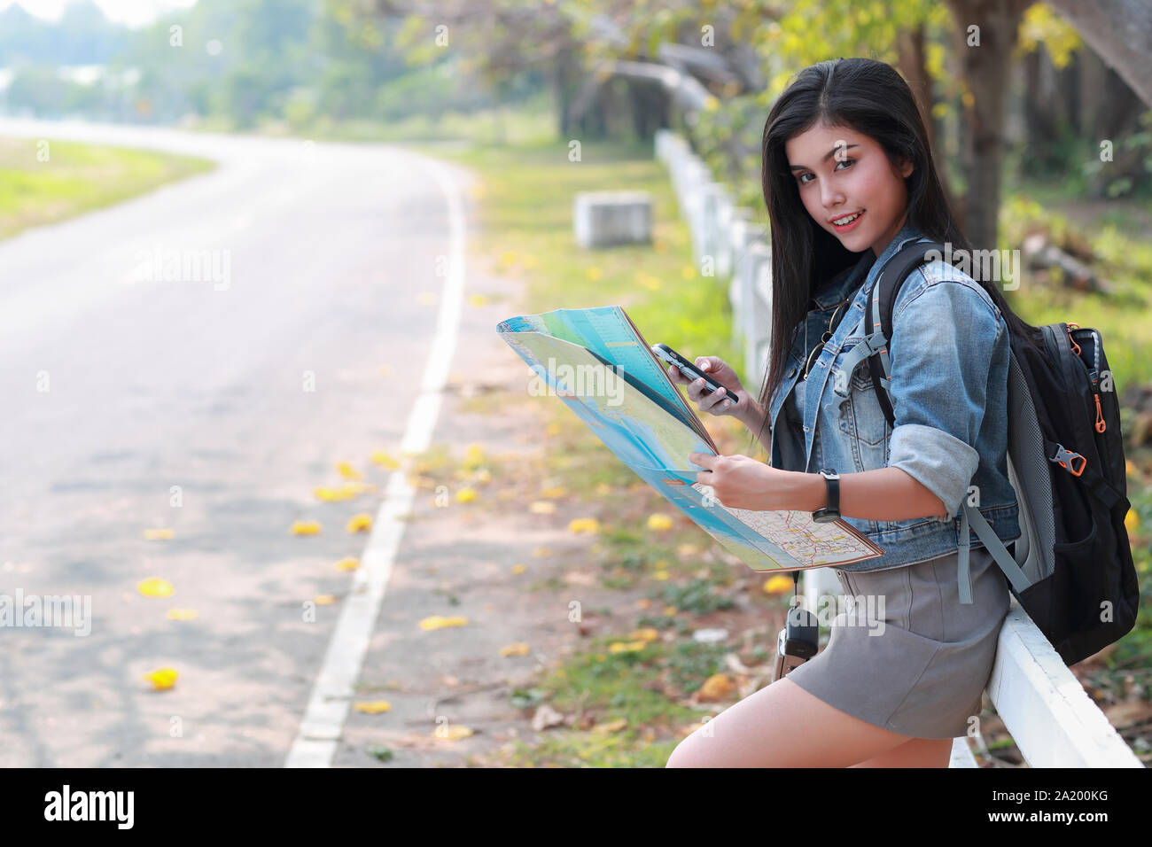 Young asian traveler searching direction on location map while traveling during holiday vacation Stock Photo